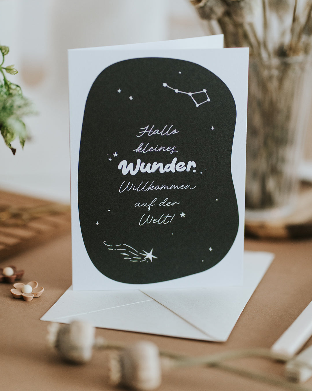 Geburtskarte mit Sternschnuppe und stilvoller Schrift, aufgestellt mit passendem Umschlag
