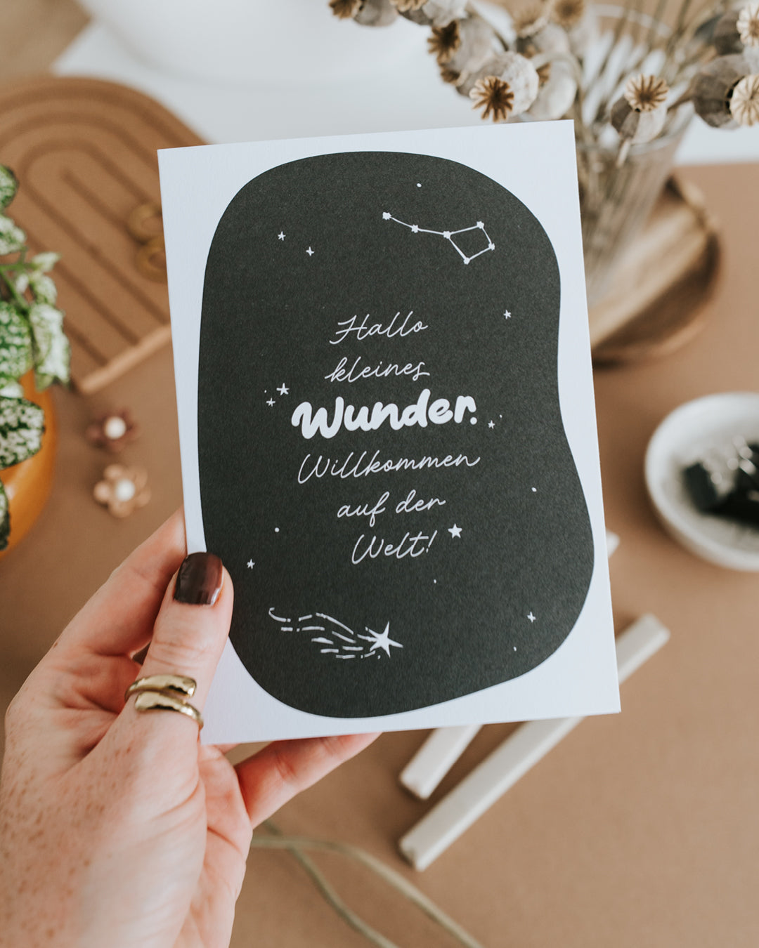 Hand hält Klappkarte „Hallo kleines Wunder. Willkommen auf der Welt!" auf hochwertigem Papier