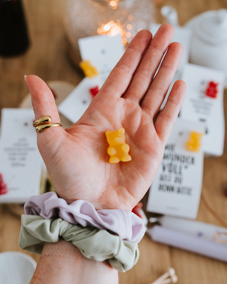 Hand hält ein gelbes Teebärchen – als Tee aufgießen oder direkt naschen.