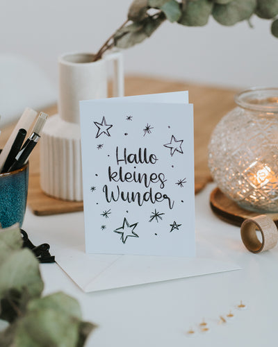Klappkarte zur Geburt „Hallo kleines Wunder" aufgestellt vor Umschlag, stilvolles Schwarz-Weiß-Design