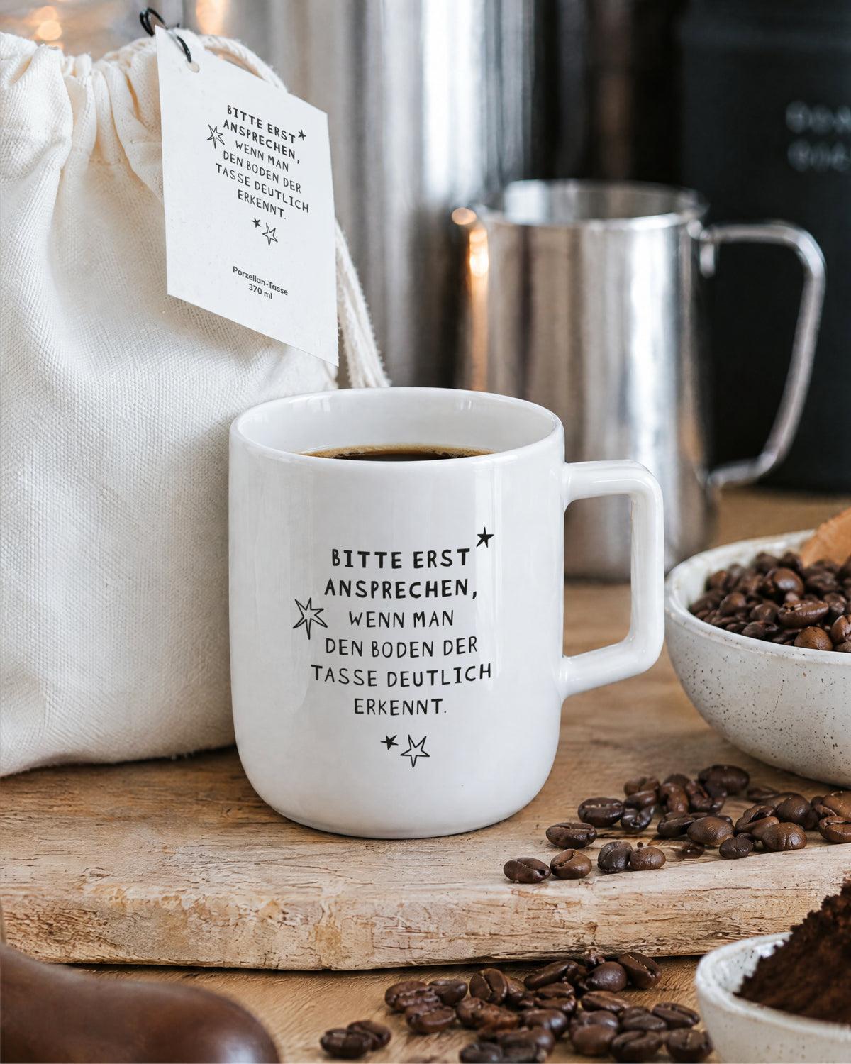 Porzellantasse mit Kaffee auf Holzbrett, daneben Kaffeebohnen.