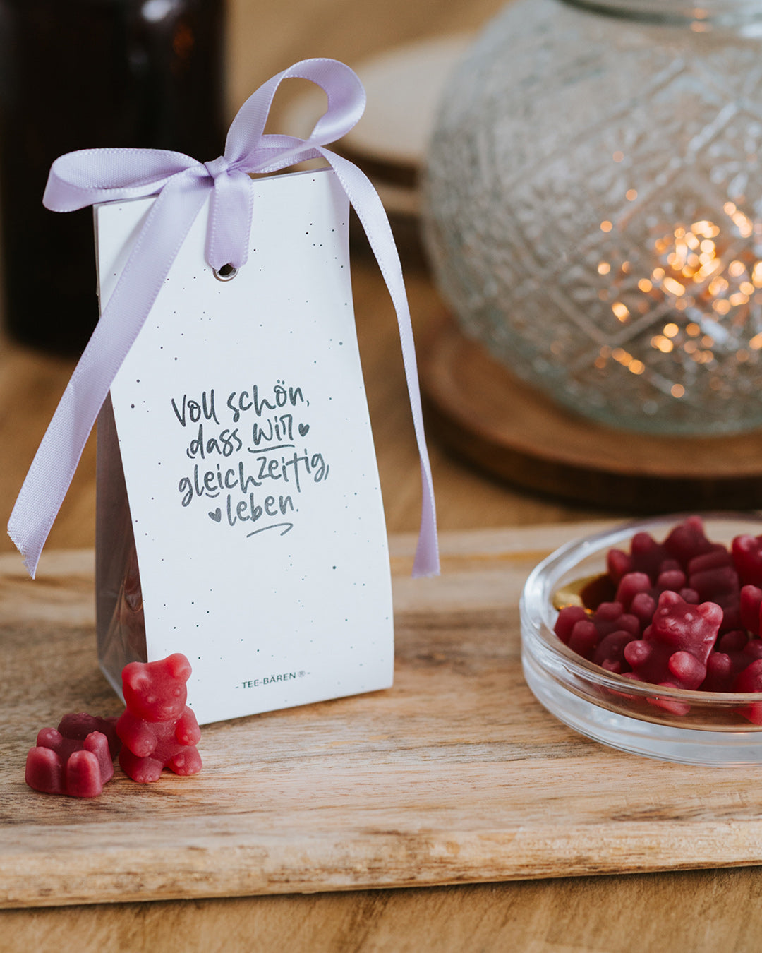 Teebären Voll schön mit fliederfarbener Schleife vor Windlicht – geschenkfertig verpackt.