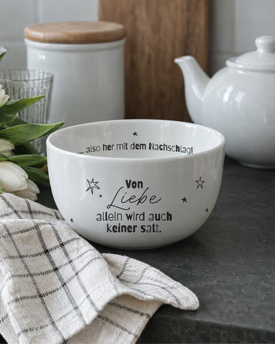 Porzellanschale „Von Liebe allein“ neben Teekanne auf dem Holztisch – weißes Porzellan.