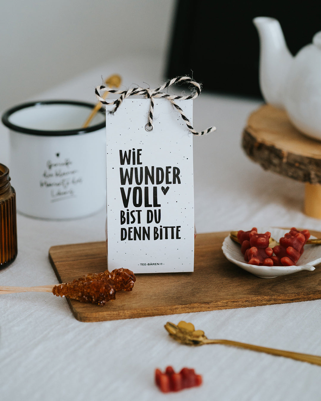 Teebären Wie wundervoll mit Kordel, daneben Emaillebecher, Teekanne und Kandiszucker.