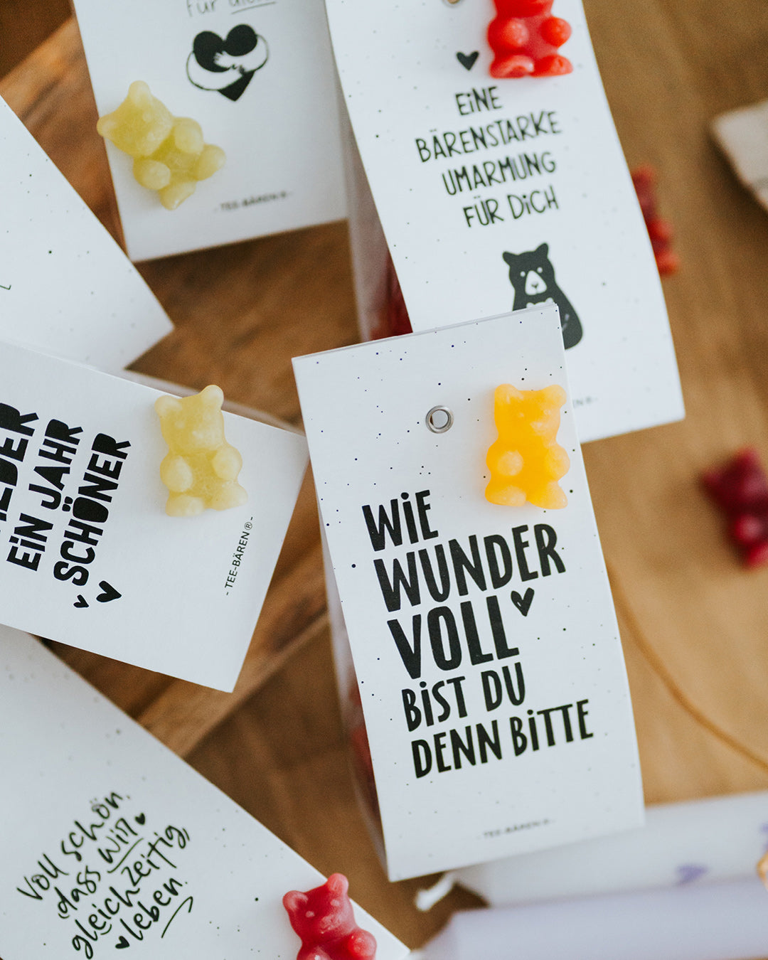 Draufsicht auf mehrere Teebären-Motive mit dunkelroten und gelben Fruchtgummi-Bärchen.