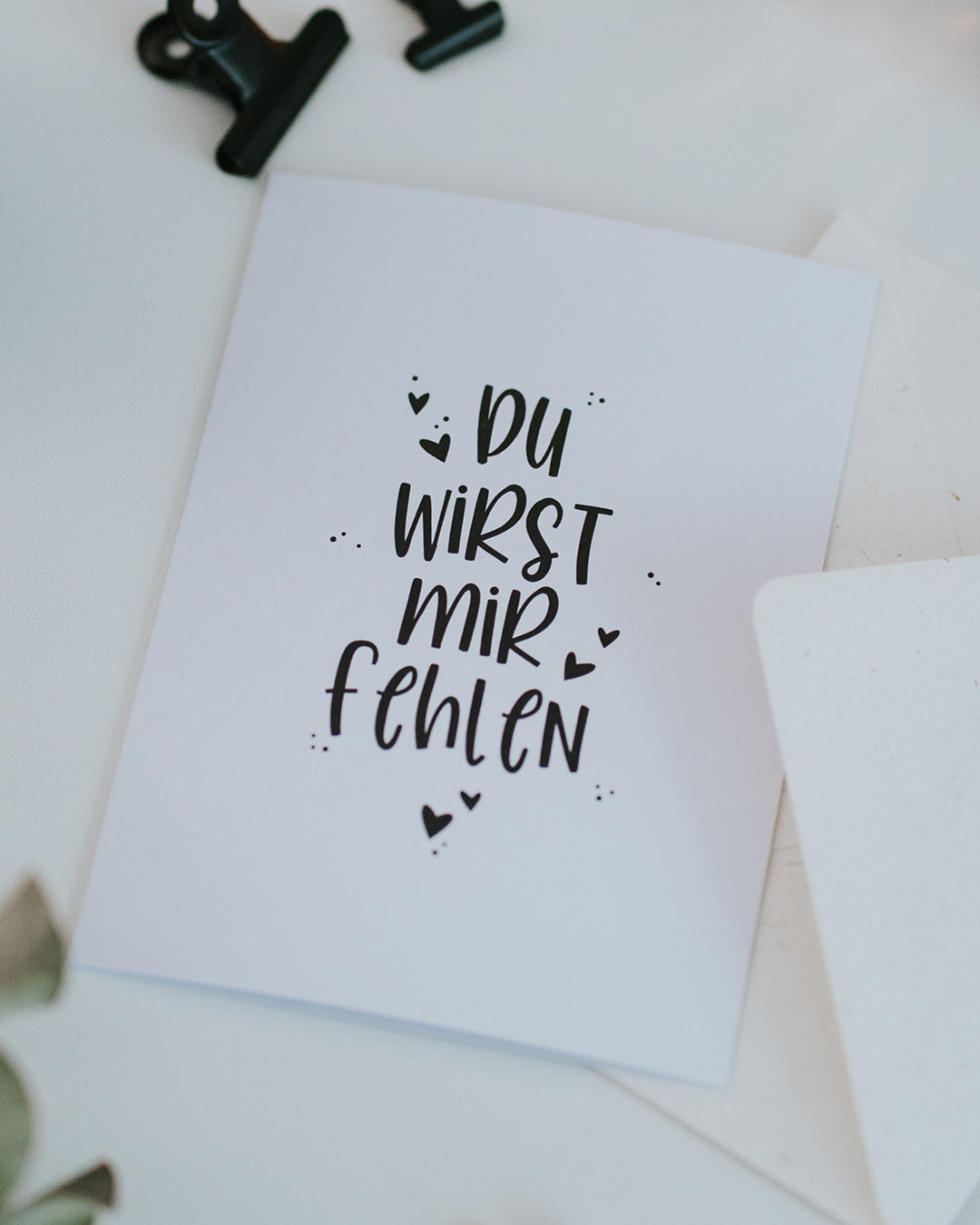 Abschiedskarte „Du wirst mir fehlen" mit geöffnetem Umschlag, schöne Typografie mit kleinen Herzen