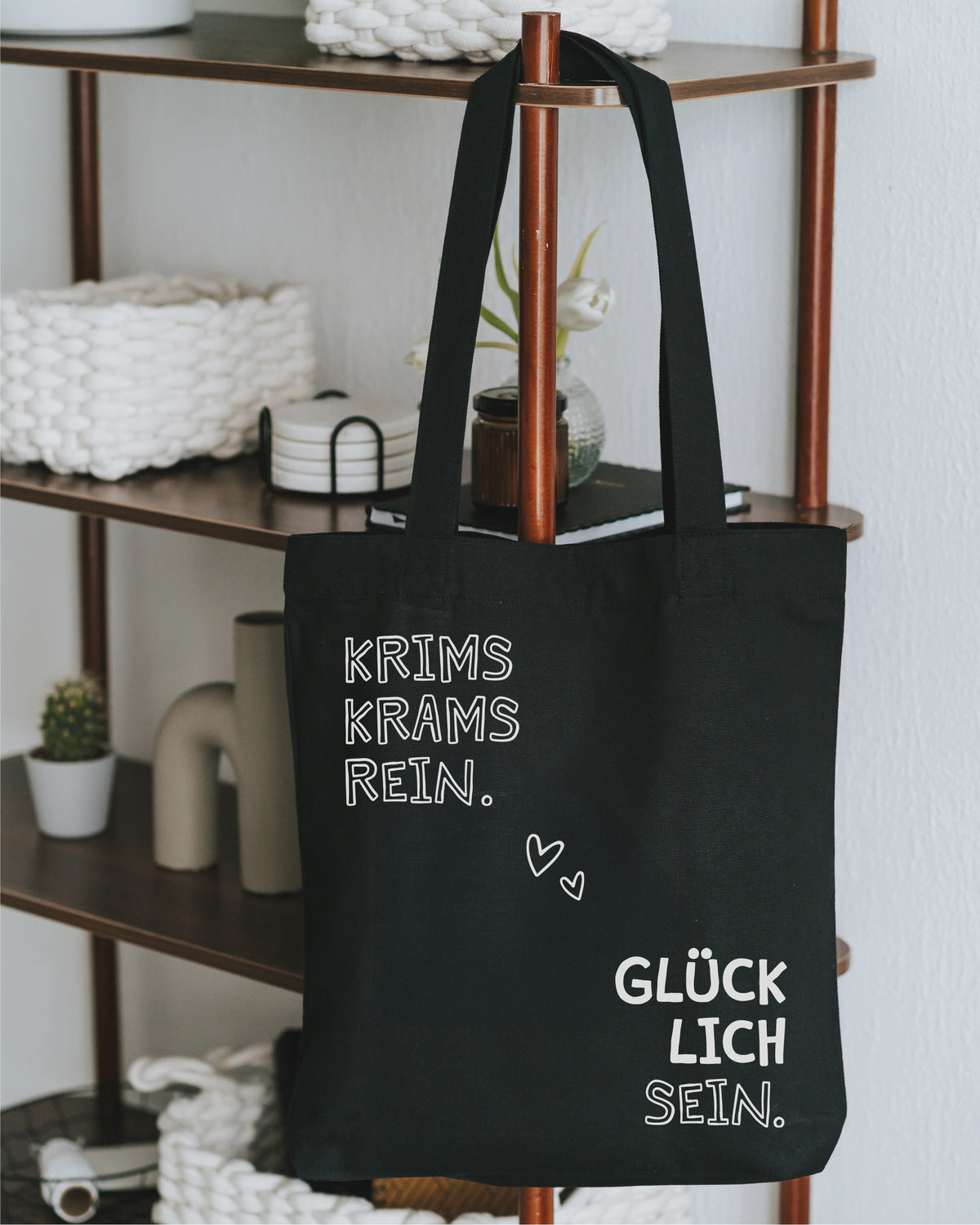 Stofftasche schwarz am Holzregal mit Korb und Tulpen – Spruch in Weiß.