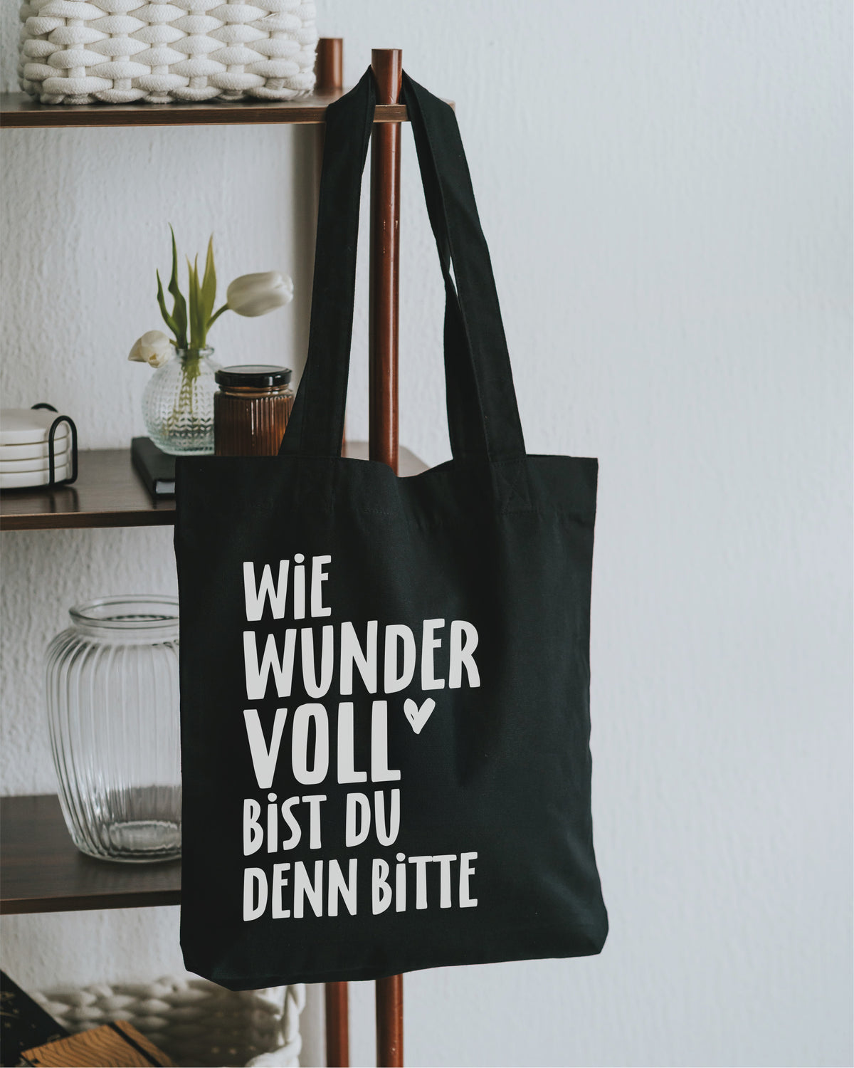 Stofftasche schwarz am Holzregal – lange Tragehenkel.