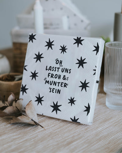 Schwarz-weiße Weihnachtsserviette mit festlicher Botschaft.