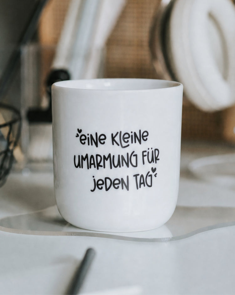 Porzellanbecher mit Spruch „Eine kleine Umarmung für jeden Tag" in Schwarz-Weiß