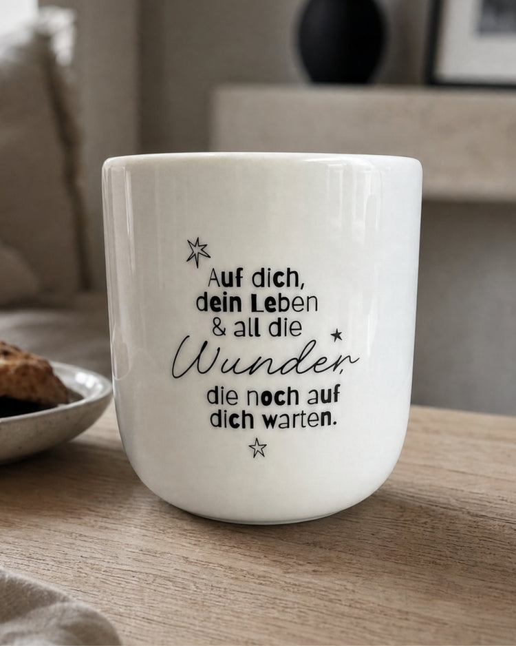 Porzellanbecher mit Spruch über Zuversicht in Schwarz-Weiß